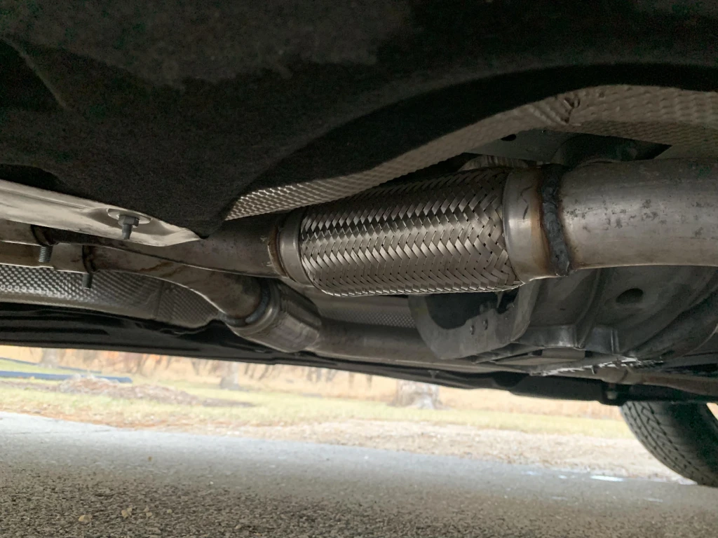exhaust flex pipe installed under car showing position between manifold and catalytic converter